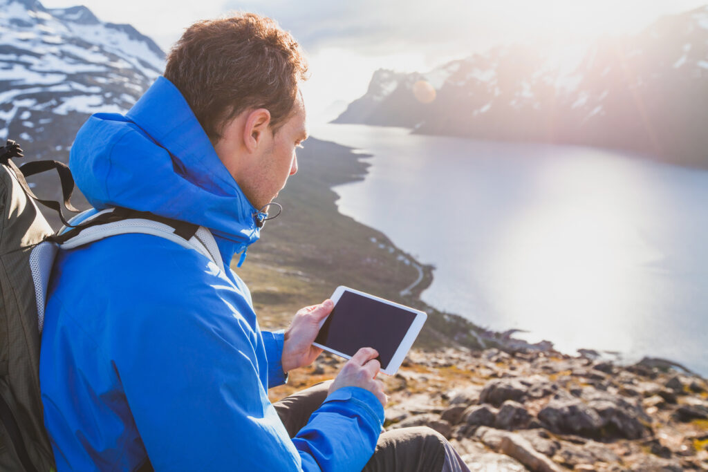Un randonneur qui utilise sa tablette pour consulter ses applications de camping
